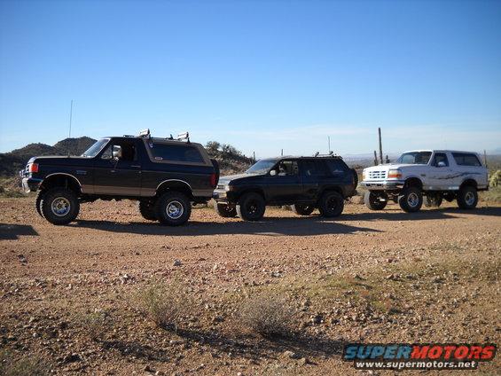 three SUVs parked on a dirt road, two are Ford Broncos and one is a Nissan Pathfinder