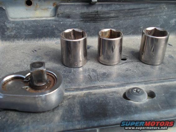 Socket wrench and three sockets on a dusty surface