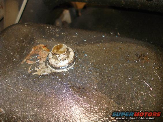 close-up of a dirty oil pan drain plug with some rust