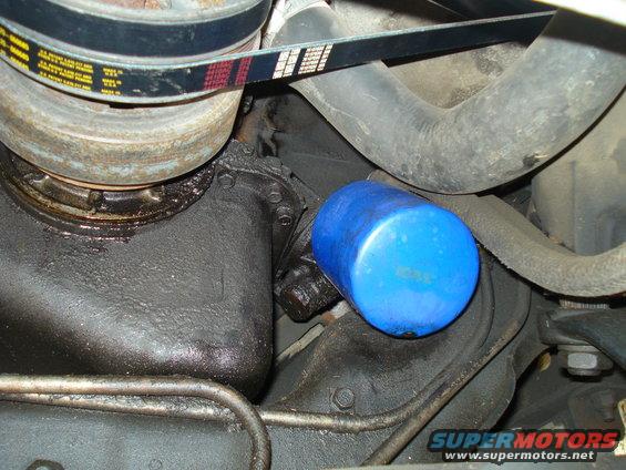 Blue oil filter and serpentine belt on a greasy engine part
