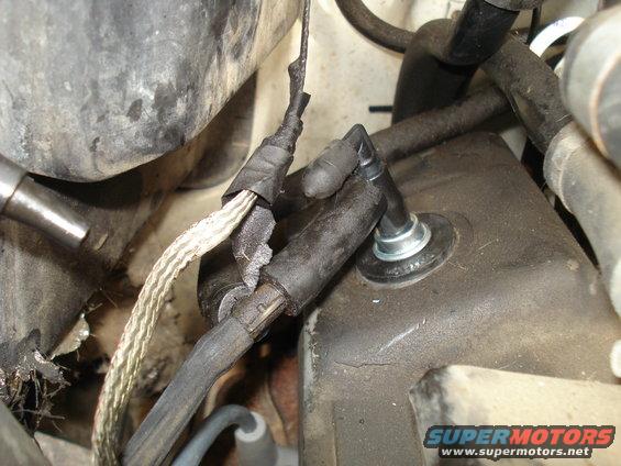Close-up of frayed wiring harness and rubber grommet in a vehicle's engine bay