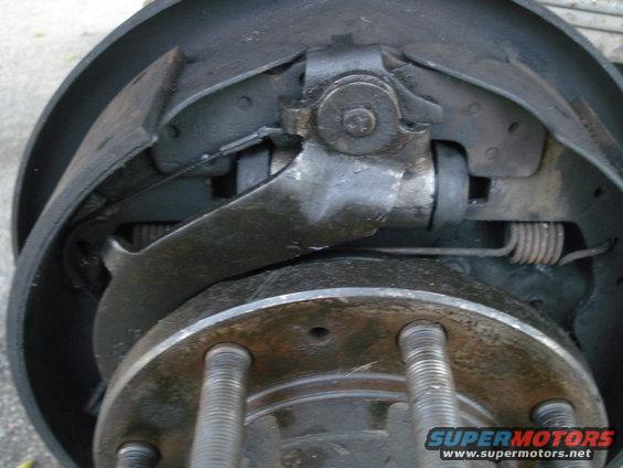 Close-up of a drum brake assembly with brake shoes, springs, and wheel studs visible