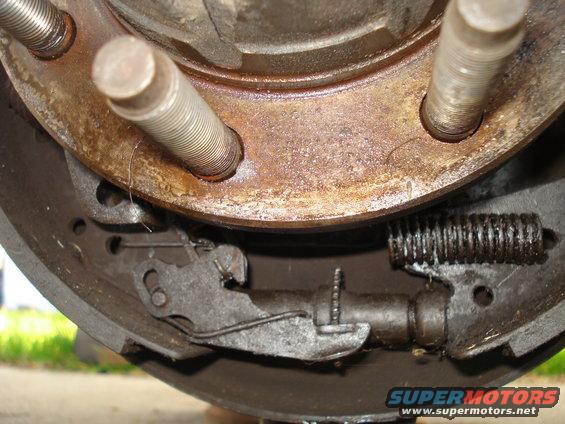Brake drum and shoes with rusty metal and springs. Text 'SUPERMOTORS' visible