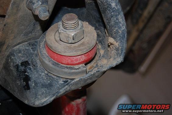 Close-up of a red suspension bushing with a bolt and nut