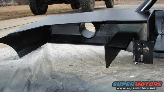 Black metal fabrication with a circular hole, resting on plastic sheeting