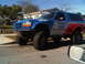 1986 Ford Bronco - A modified Ford Bronco with racing livery is seen from the front-quarter angle on a sunny day.