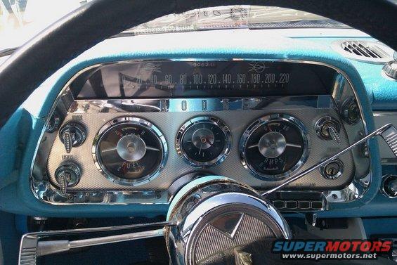 Car dashboard with round gauges, speedometer, and steering wheel. Blue interior trim