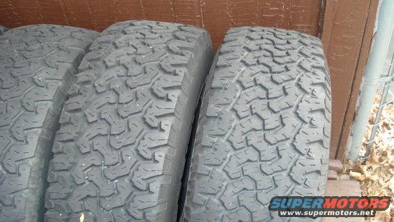 Four off-road tires with aggressive tread patterns, side-by-side