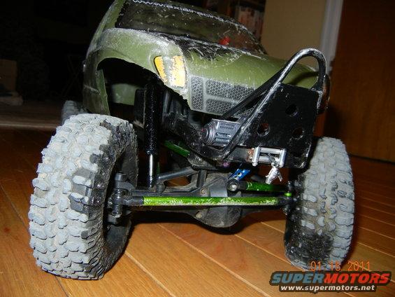 RC car chassis with large tires, green suspension components, and a black bumper