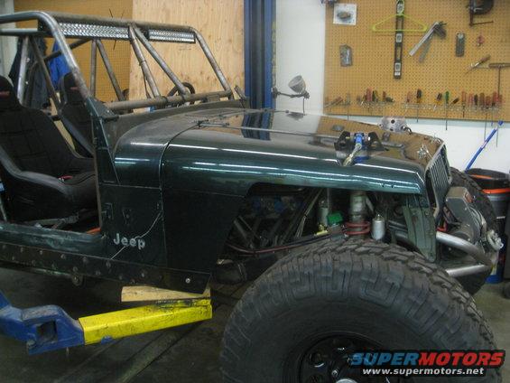 Green 1994 Jeep YJ with custom roll cage and off-road tires in a workshop