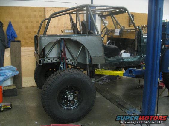 1994 Jeep YJ body with custom roll cage, unfinished metal panels, and large tires, on a lift