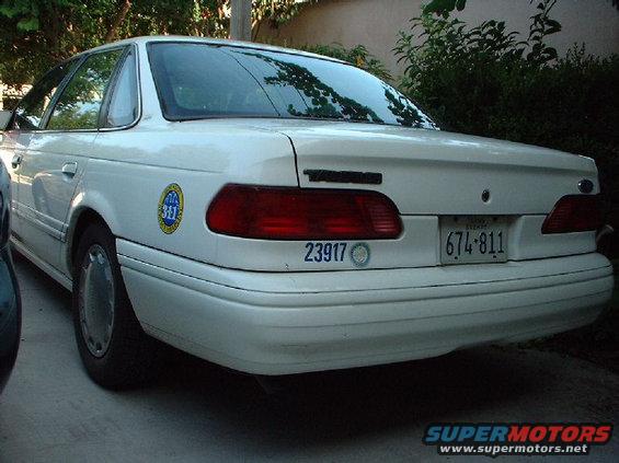 Rear view of a white 1996 Ford Taurus with a license plate 674-811 and a '311' sticker