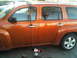 1986 Ford Bronco - An orange SUV is parked next to another vehicle, with a rope secured to its roof rack.