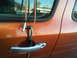 1986 Ford Bronco - Cable lock on an orange vehicle door, with reflections of buildings and a bus in the window.