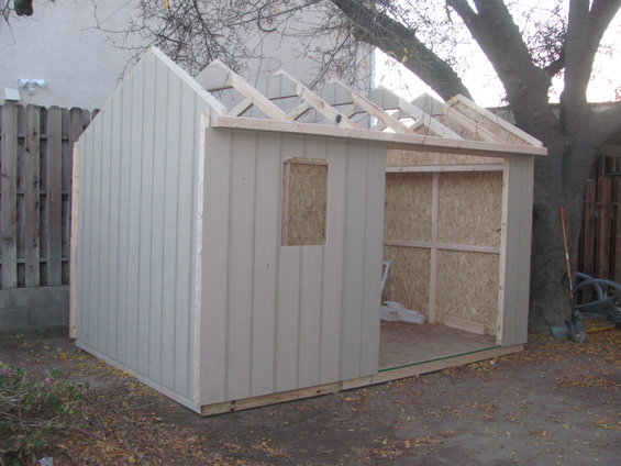 shed being built, unfinished roof rafters, window opening, and interior framing visible