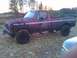 1988 Ford F-250 - This red pickup truck is heavily covered in mud, suggesting it has been used off-road.