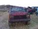 1988 Ford F-250 - A muddy red pickup truck sits in a field with another vehicle in the background.