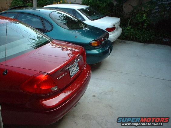 Red sedan's rear end, teal sedan behind it, white sedan behind that. License plate V75 LYN
