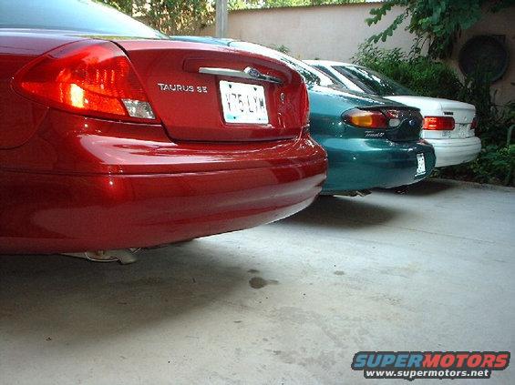 Red 1996 Ford Taurus SE rear view, license plate V75 LYM, parked next to green and white cars