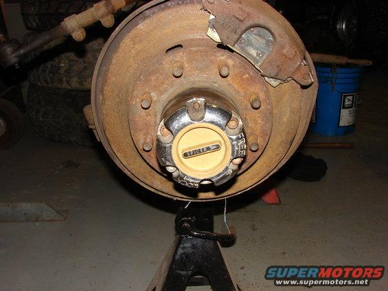 Rusty wheel hub with a yellow Spicer cap, supported by a jack stand