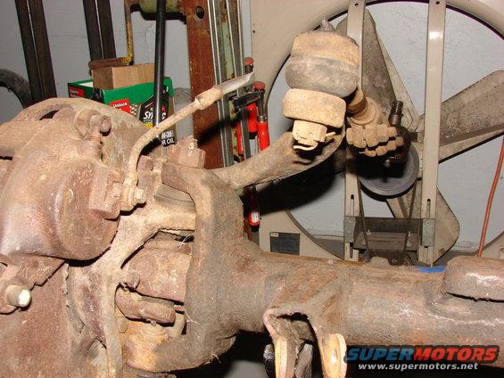 Close-up of a rusty vehicle suspension component, possibly a steering knuckle or axle housing