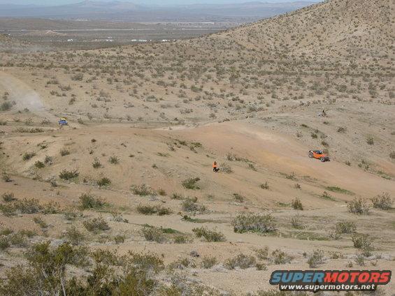 Orange off-road buggy and blue off-road buggy driving in a desert landscape