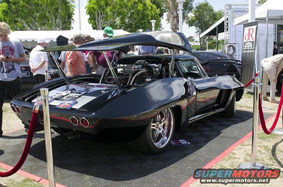 Black custom Corvette with open hood showing engine, lowered suspension, and chrome wheels