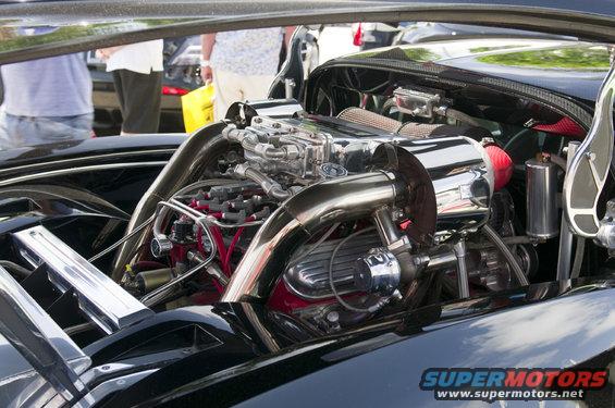 Black car engine with chrome intake and red spark plug wires