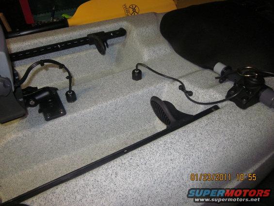 Kayak interior with foot braces, mounting hardware, and a yellow paddle visible