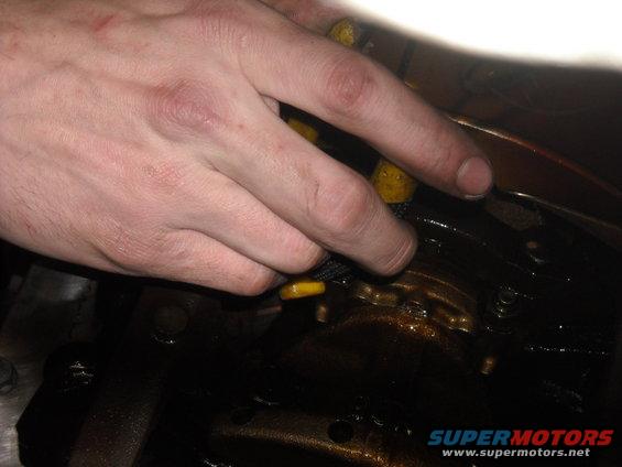 hand using tool on greasy engine component