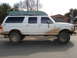 1992 Ford C-350 (Centurion Conversions) - This 1992 Ford C-350 Centurion Conversions truck is seen from the side, carrying a boat on its roof and covered in mud.