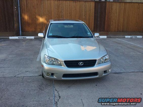 Silver Lexus IS300 parked in front of a wooden fence