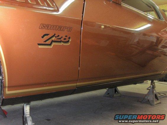 1982 Chevrolet Camaro Z28 side view, orange paint with gold stripe, on jack stands
