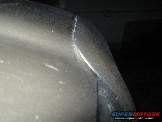 Close-up of a car's metallic gray fender and bumper corner, showing a seam between the two parts