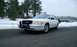 1999 Ford Crown Victoria - A white Ford Crown Victoria is parked on a road with snow-covered ground and trees.