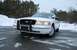 1999 Ford Crown Victoria - A white 1999 Ford Crown Victoria police car is parked on a wet road with snow in the background.