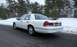 1999 Ford Crown Victoria - A white sedan is viewed from the rear on a road with snow-covered trees in the background.