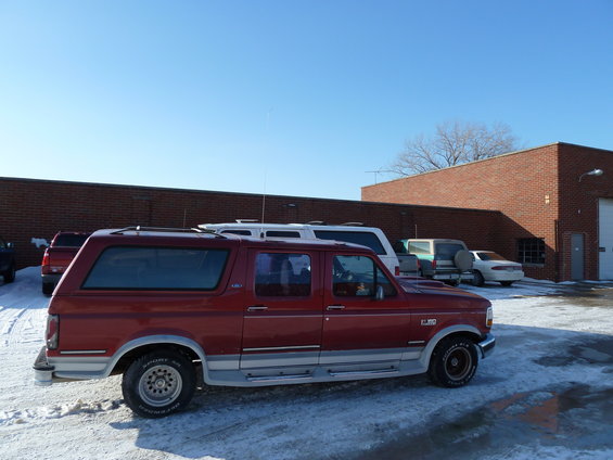 Red Ford Bronco SUV parked next to a white van and other vehicles in a snowy lot