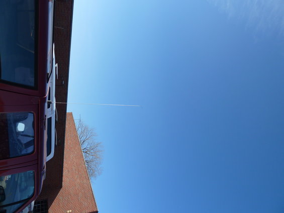 Side view of a red van parked next to a brick building under a clear blue sky