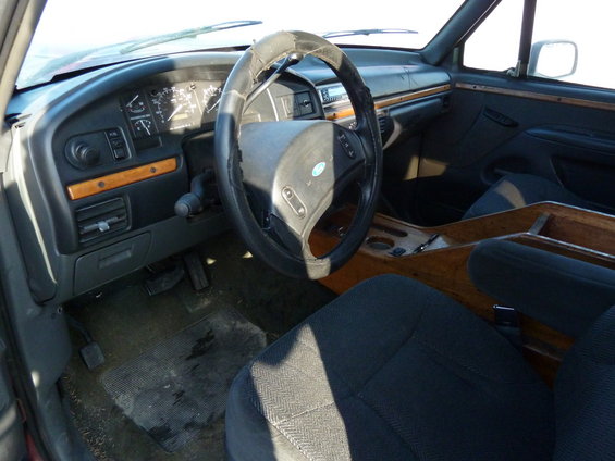 Truck interior with wood trim, dark seats, and dashboard gauges. The steering wheel is worn