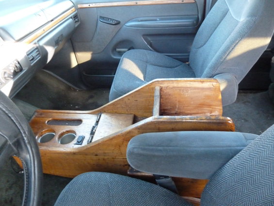 Interior of a van with cloth seats and a custom wooden center console with cup holders