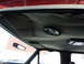 1993 Ford C-150 (Centurion Conversions) - The interior ceiling of a vehicle shows a speaker and a sun visor, with a rearview mirror reflecting the outside.