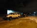 1993 Ford C-150 (Centurion Conversions) - White Ford SUV towing a car on a trailer at night in a parking lot.