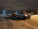 1993 Ford C-150 (Centurion Conversions) - White Ford SUV towing a dark pickup truck at night in a snowy lot.