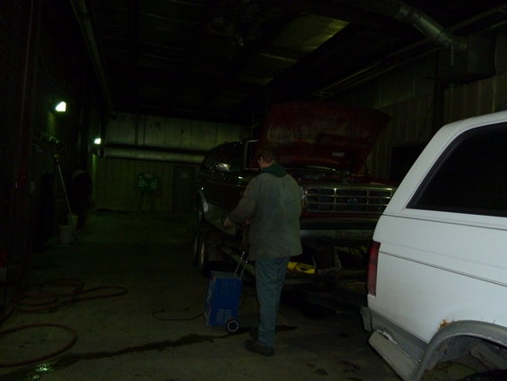 Ford F-Series truck with hood open on a trailer, white vehicle to the right