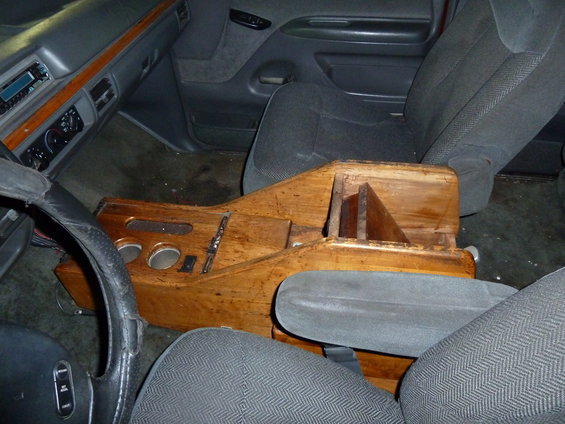Interior view of a vehicle with a custom wooden center console and gray seats