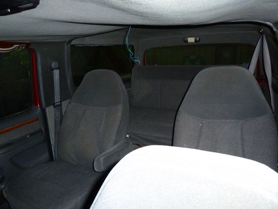 Interior view of a van or large SUV showing front bucket seats and a rear bench seat