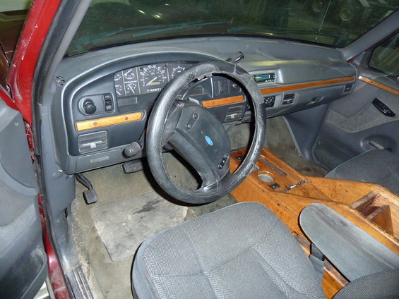 Interior view of a red truck, showing dashboard, steering wheel, and seats. Custom wood console is visible