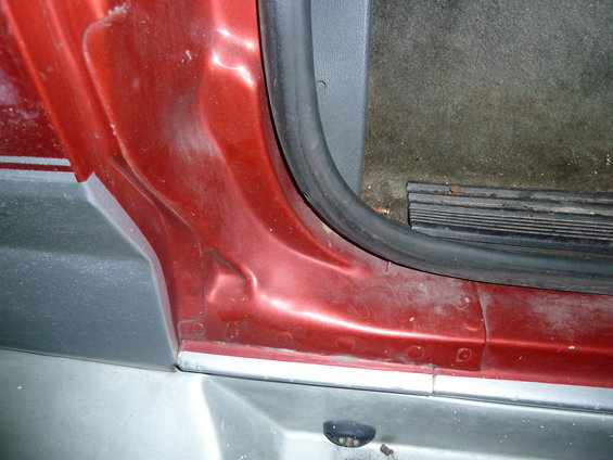 Red door jamb with gray trim and black rubber seal. Interior carpet visible