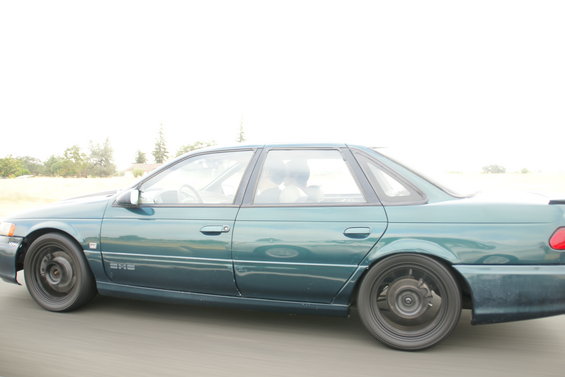Green 1995 Ford Taurus sedan, side view, with black wheels and tinted windows